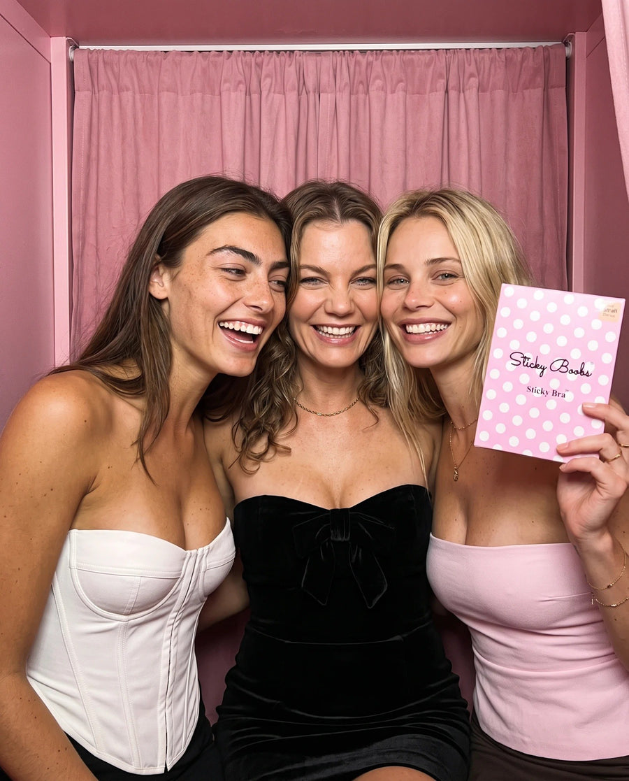 Three friends laughing in a pink photo booth