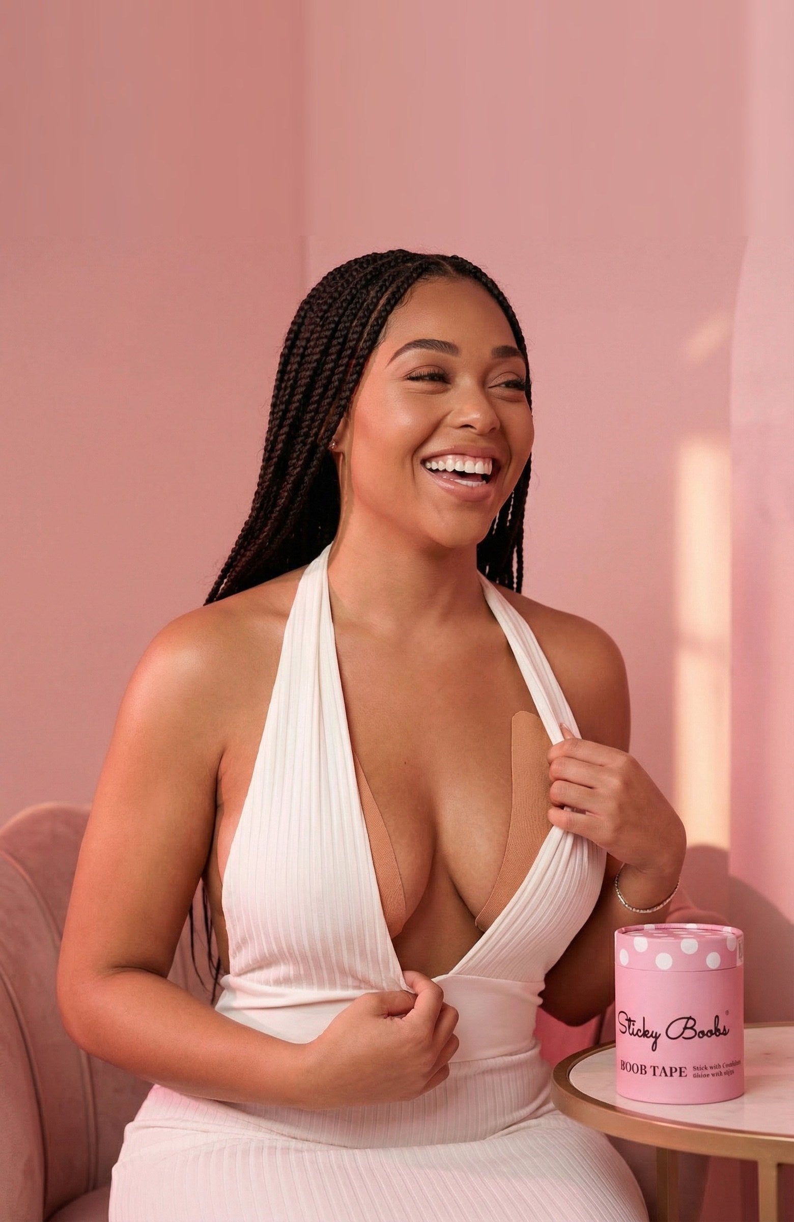 Woman in a white plunge halter dress next to a roll of Boob Tape